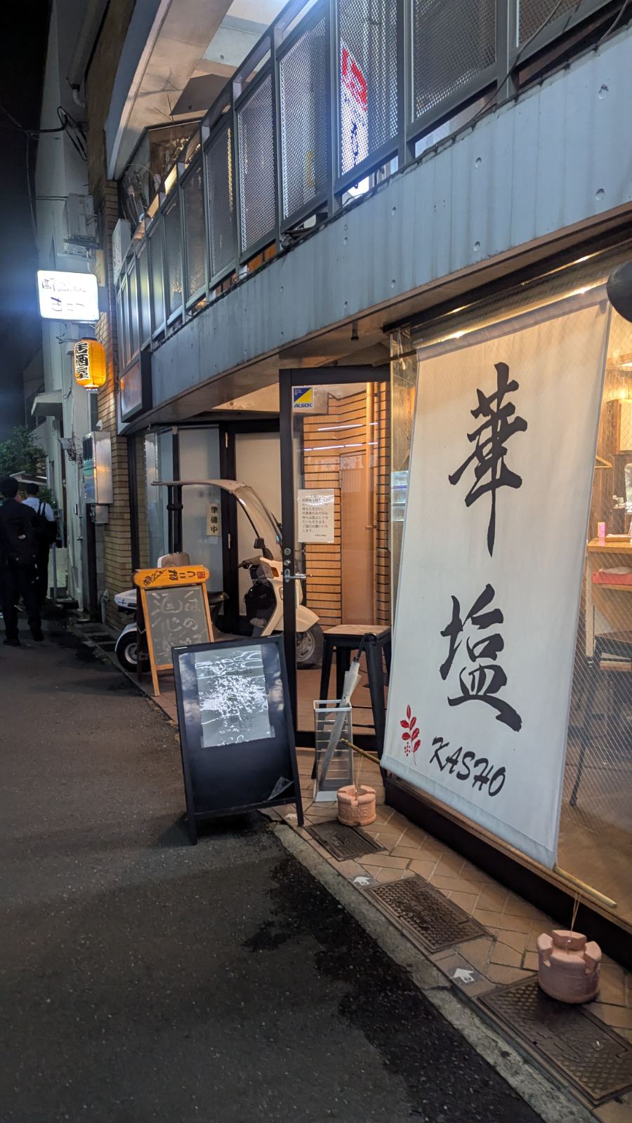 Night view of Ramen Kasho storefront with its white noren curtain